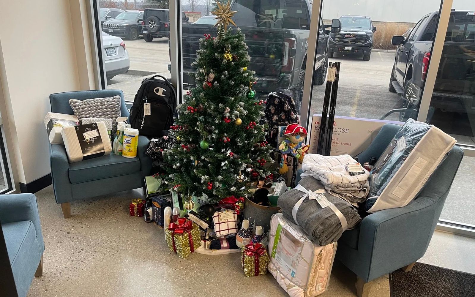 Donated bedding, backpacks, and wrapped gifts gathered around a Christmas tree in the Jackman office during the 2024 Angel Tree holiday drive.