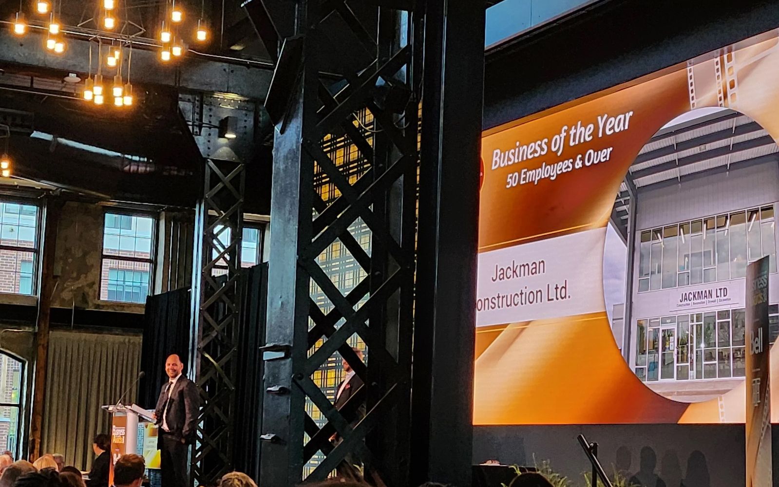 A stage screen announcing Jackman Construction Ltd. as Business of the Year, 50 Employees and Over.
