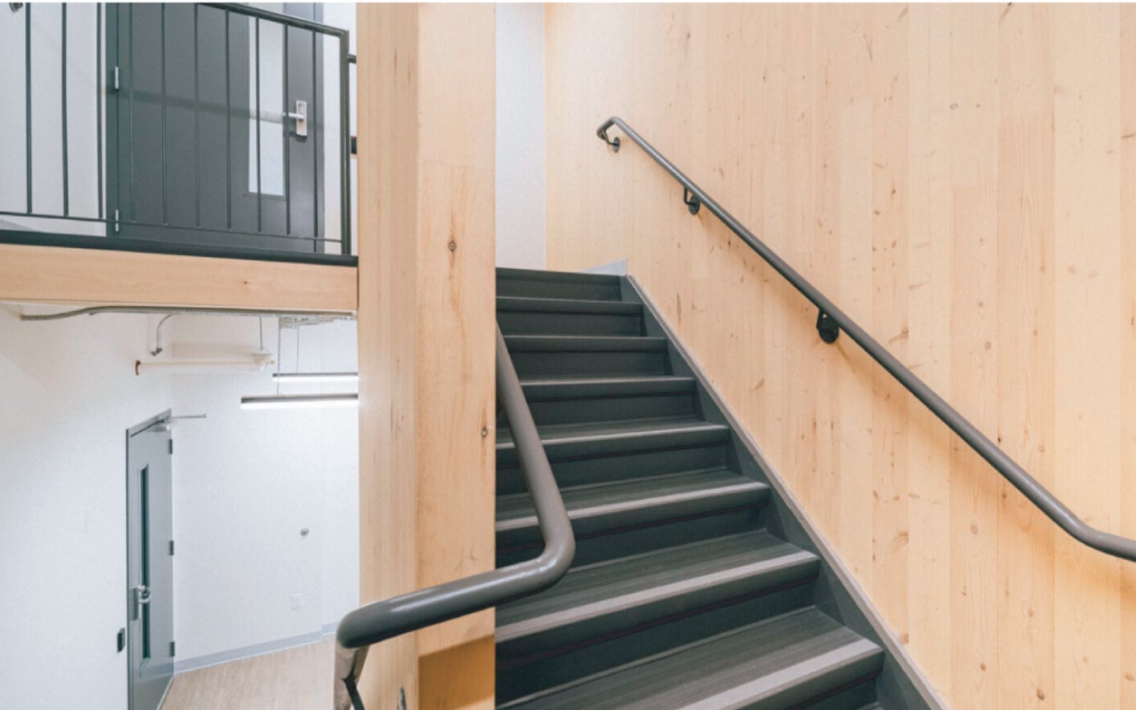 Stairwell at Passage House with exposed mass timber walls and dark treads.
