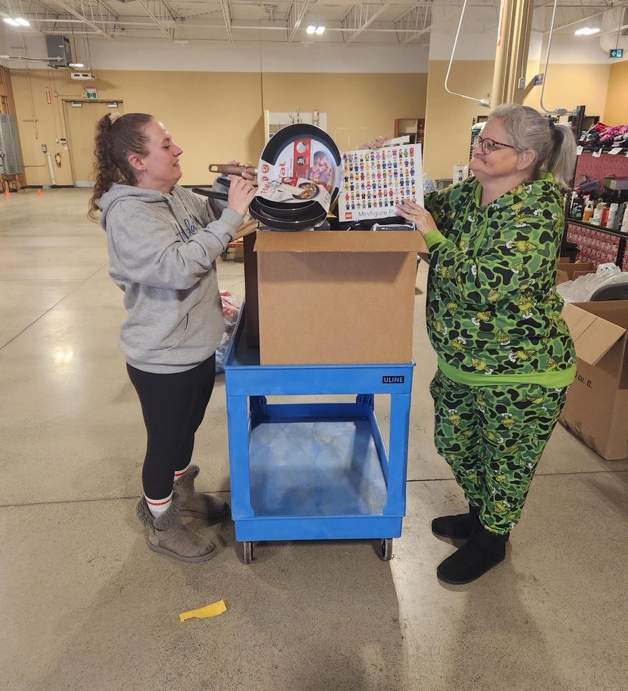 Two people sort donated toys and household goods from a box on a cart during Jackman's 2024 Angel Tree holiday drive.