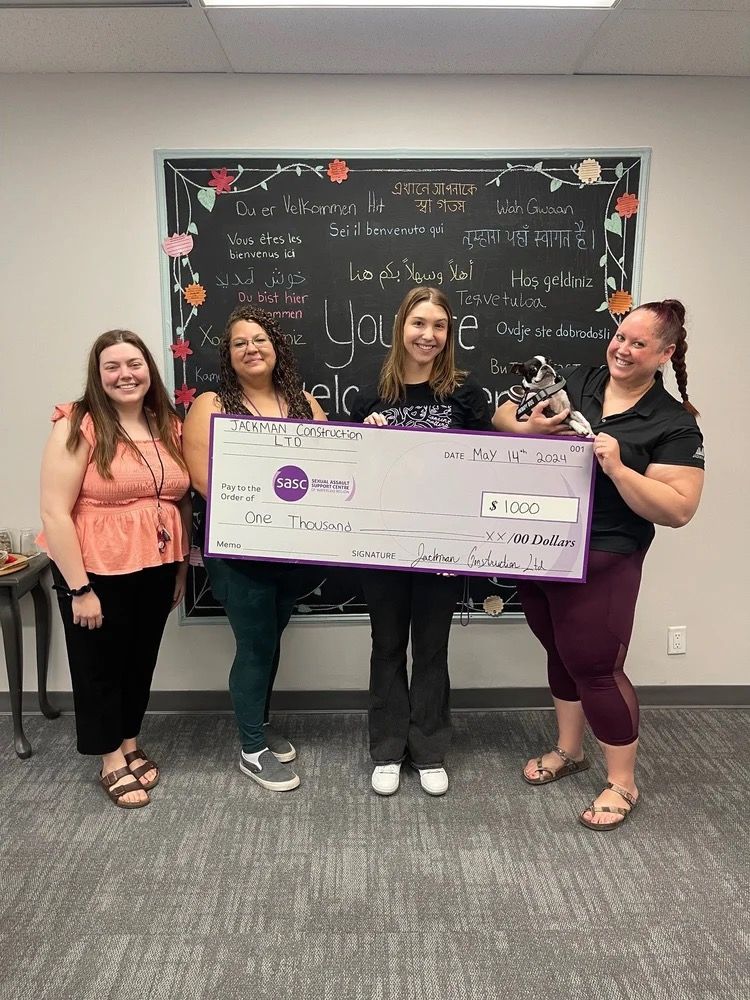 Jackman Construction and SASCWR staff holding a $1,000 ceremonial cheque for the Sexual Assault Support Centre of Waterloo Region, with therapy dog Ellie.