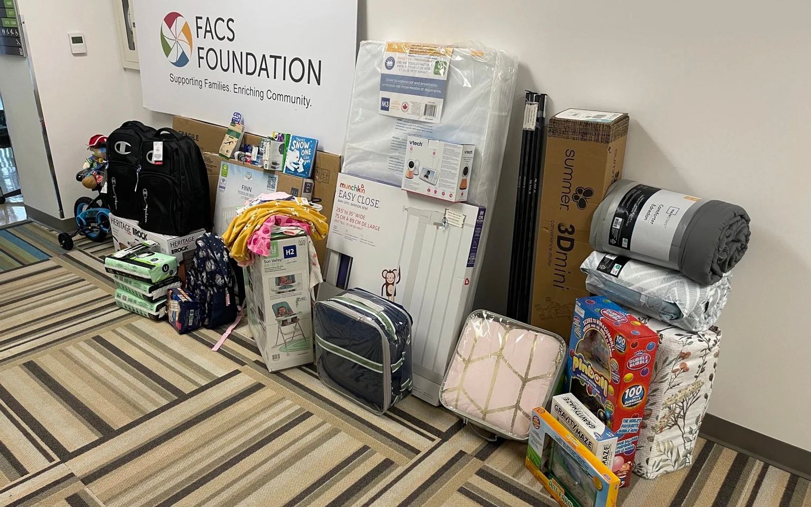 Toys, baby gear, and household goods stacked under a Family and Children's Services Foundation sign.