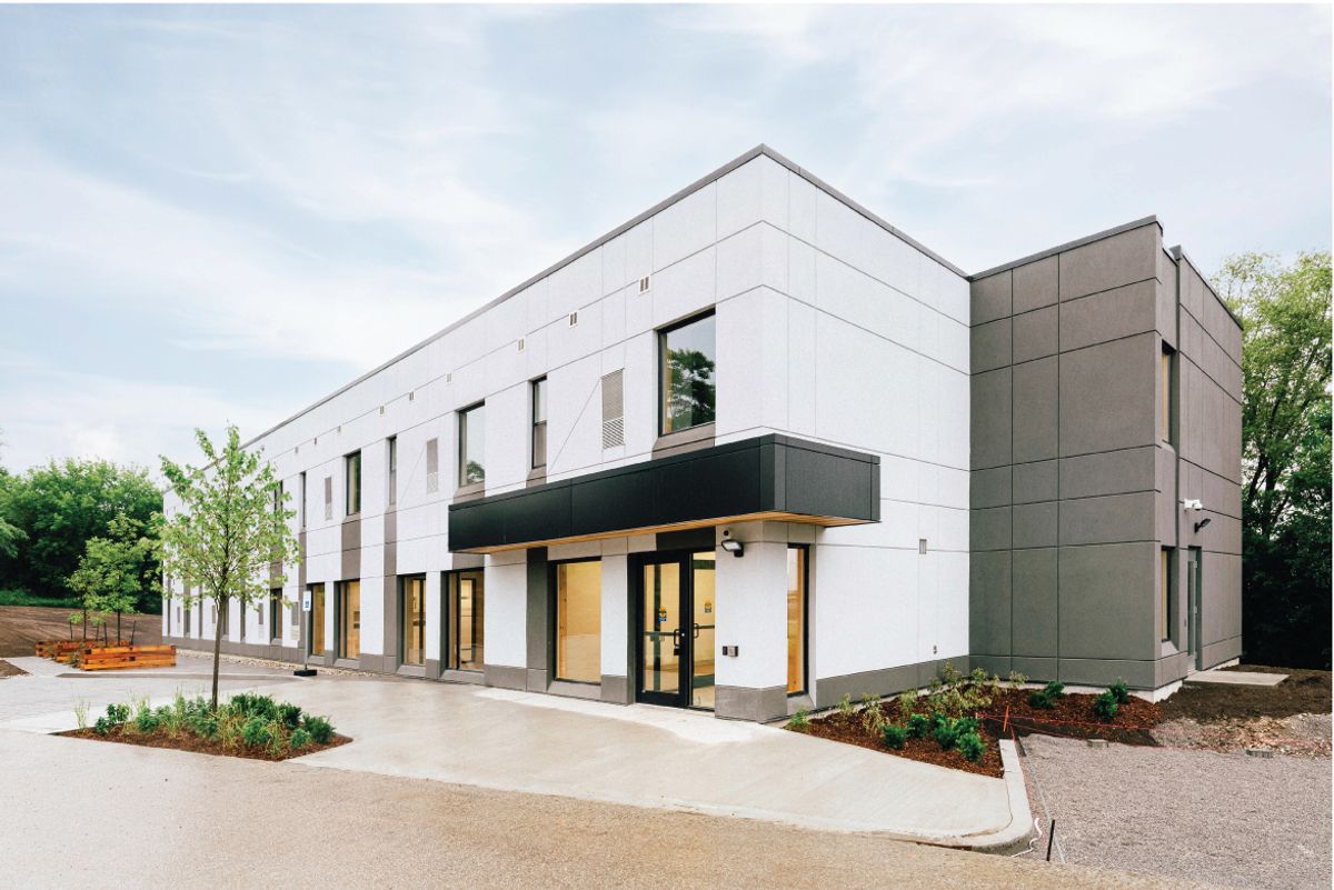 Exterior of Passage House, a two-storey mass timber transitional housing building in East Gwillimbury, with a wood-lined entrance canopy.