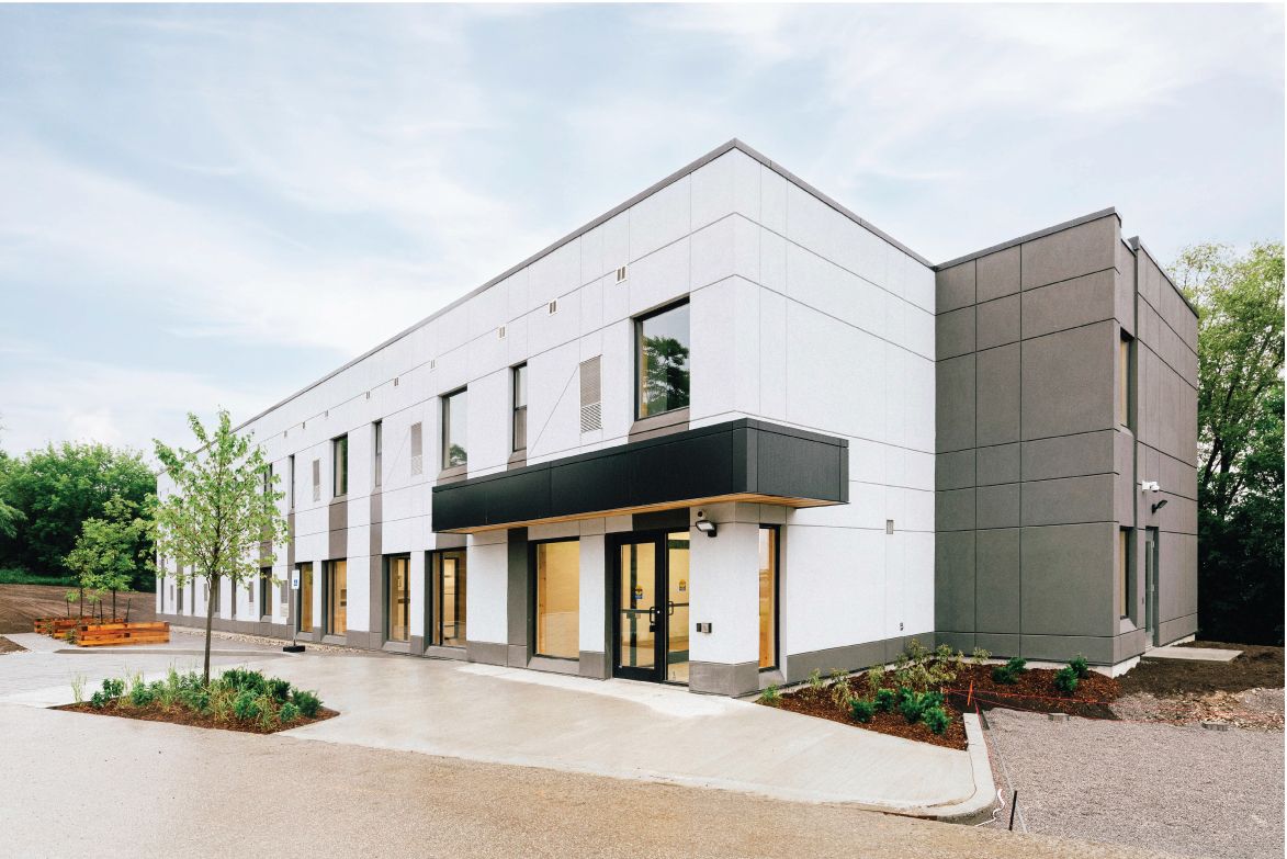 Exterior of Passage House, a two-storey mass timber transitional housing building in East Gwillimbury, with a wood-lined entrance canopy.