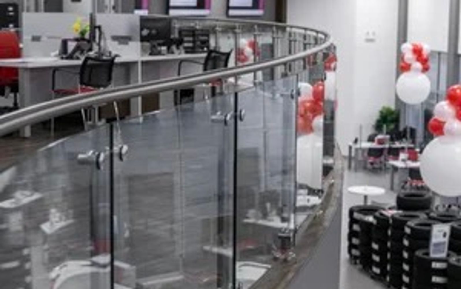 Curved glass and metal mezzanine railing overlooking the Cambridge Honda showroom.