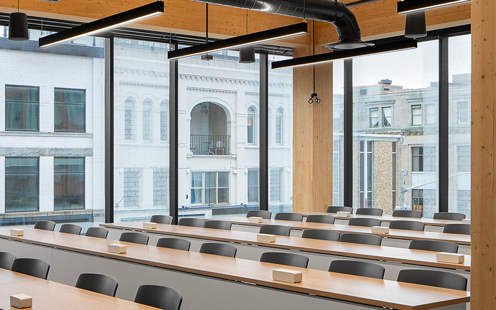 A bright workspace at One Young Street with glulam columns, an NLT ceiling, and floor-to-ceiling windows onto downtown Kitchener.