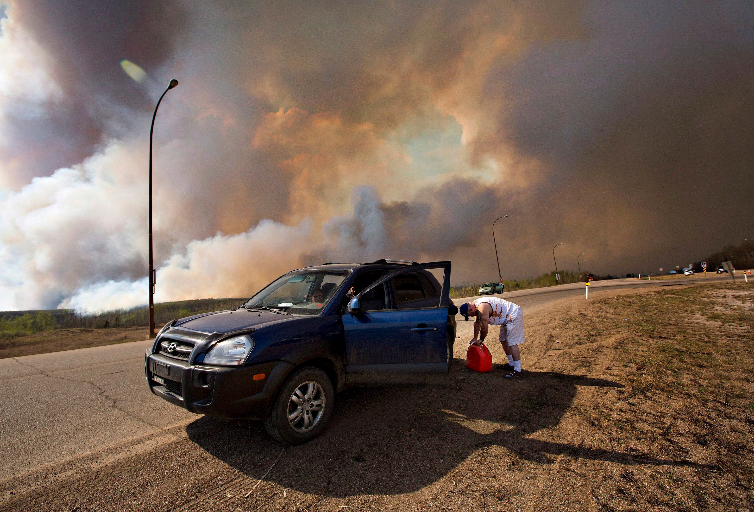 An evacuee puts gas in his car on his way out of Fort McMurray, Alta., on Wednesday May 4, 2016. The wildfire has already torched 1,600 structures in the evacuated oil hub of Fort McMurray and is poised to renew its attack in another day of scorching heat and strong winds.THE CANADIAN PRESS/Jason Franson