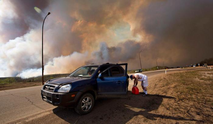 An evacuee puts gas in his car on his way out of Fort McMurray, Alta., on Wednesday May 4, 2016. The wildfire has already torched 1,600 structures in the evacuated oil hub of Fort McMurray and is poised to renew its attack in another day of scorching heat and strong winds.THE CANADIAN PRESS/Jason Franson