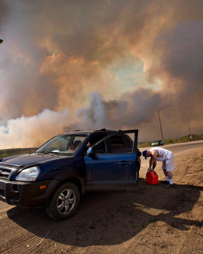 An evacuee puts gas in his car on his way out of Fort McMurray, Alta., on Wednesday May 4, 2016. The wildfire has already torched 1,600 structures in the evacuated oil hub of Fort McMurray and is poised to renew its attack in another day of scorching heat and strong winds.THE CANADIAN PRESS/Jason Franson