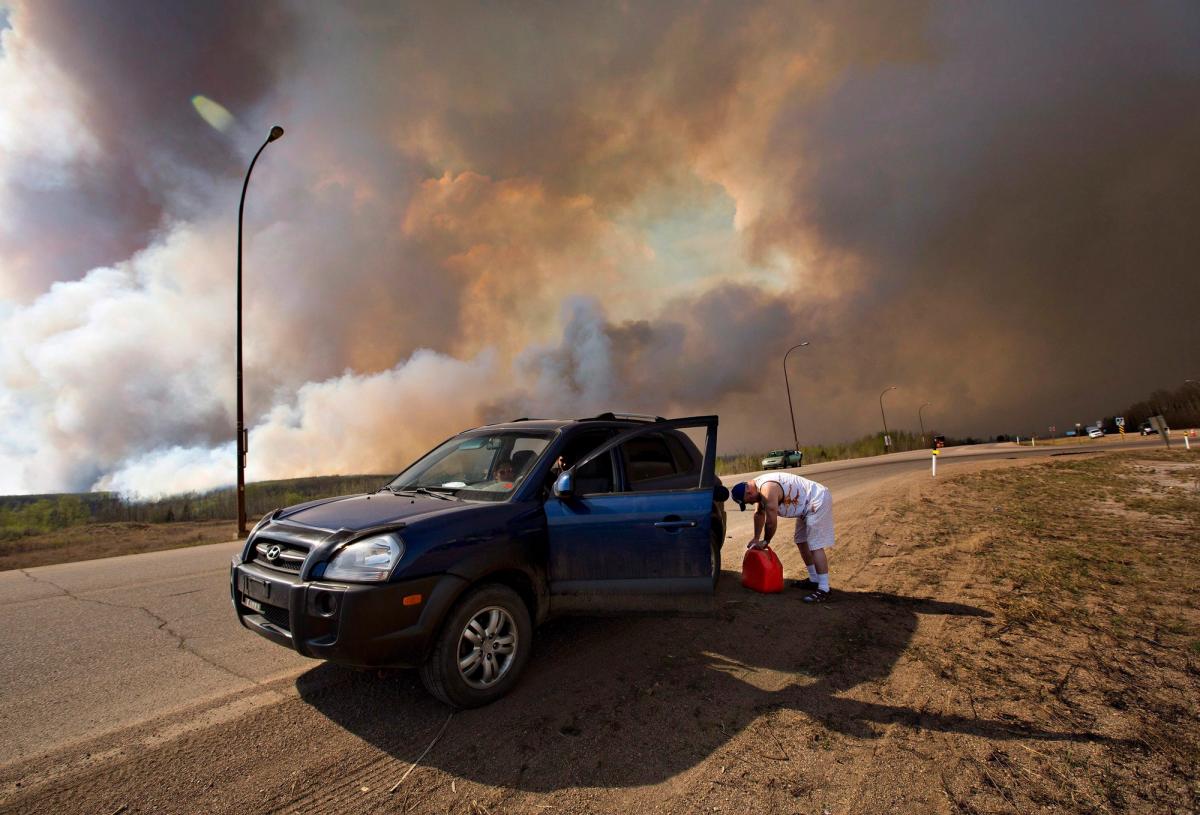 An evacuee puts gas in his car on his way out of Fort McMurray, Alta., on Wednesday May 4, 2016. The wildfire has already torched 1,600 structures in the evacuated oil hub of Fort McMurray and is poised to renew its attack in another day of scorching heat and strong winds.THE CANADIAN PRESS/Jason Franson