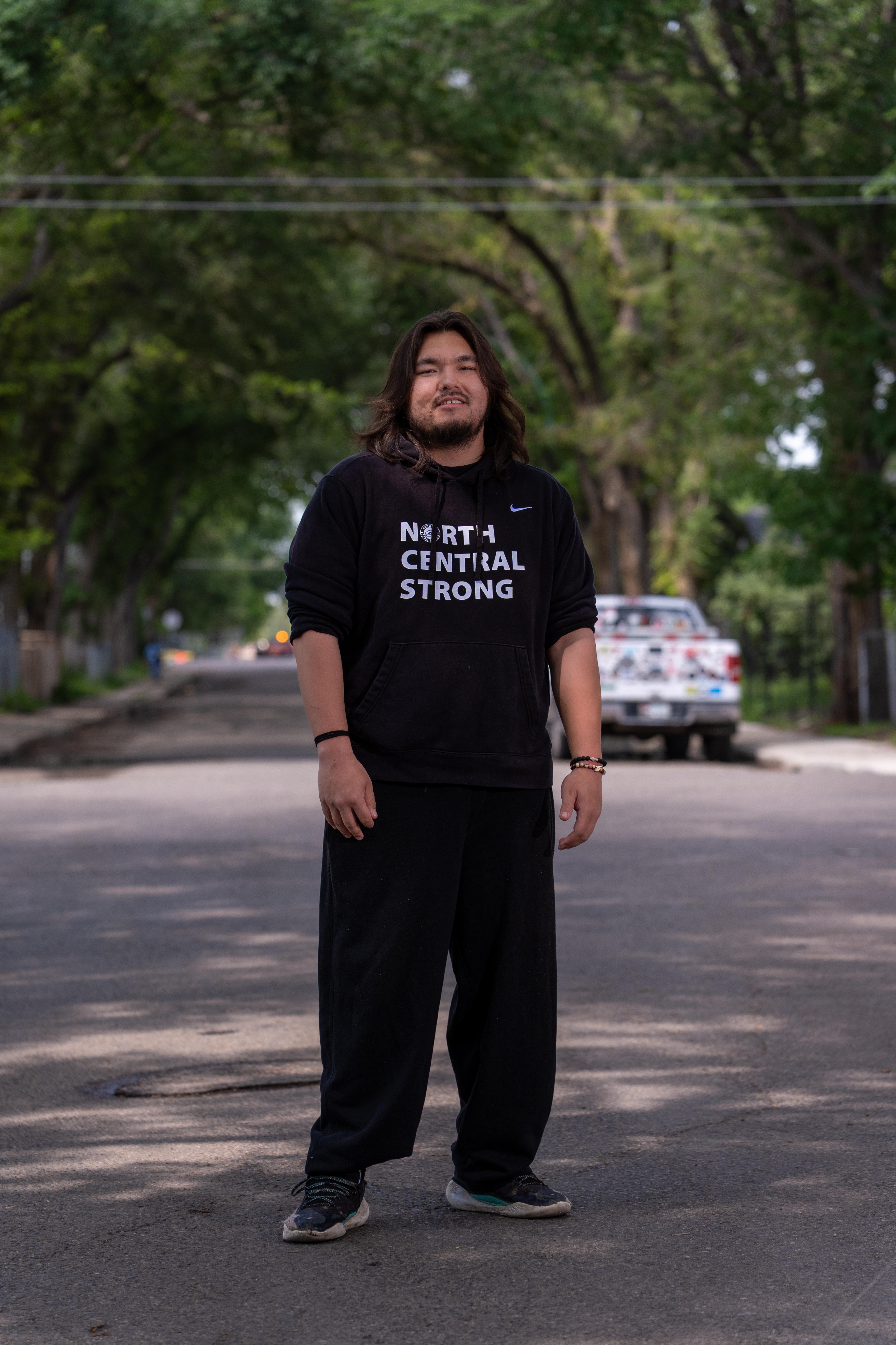 Joseph Klyne stands in a street wearing a North Central Strong hoodie.