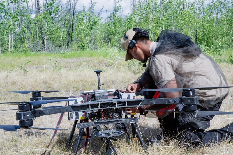 A Wildfire Quest team member prepares a drone in the field near Nenana, Alaska, on June 16, 2026. After the teamâs original suppressant capsule failed to receive FAA approval, it improvised with heavy-duty, vacuum-sealed bags released through a trapdoor.
