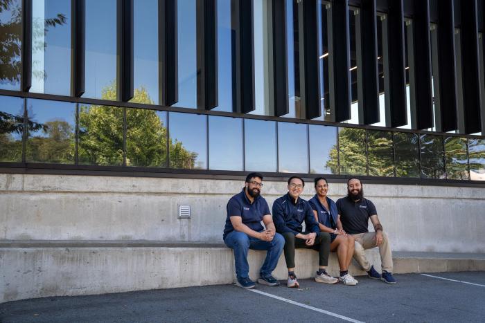 Gurmesh Sidhu, Edward Chiang, Sumreen Rattan and Gabriel Soares sit outside Moment Energy’s newest facility in Surrey, B.C. on Tuesday, June 16, 2026. The four co-founded the company in 2019 in a home garage, aiming to repurpose batteries into clean energy. Former engineering students at Simon Fraser University, the four co-founders first venture together was a meditation company. The new Surrey-based facility is expected to open by the end of June and claims to be the world’s largest in battery repurposing.