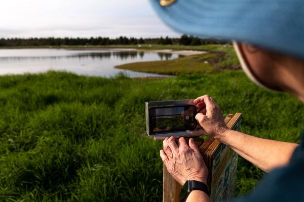 Colleen Boudreau demonstrates a citizen scientist monitoring station at Black Duck Cove Provincial Park. The frame lets onlookers snap a photo for research use.