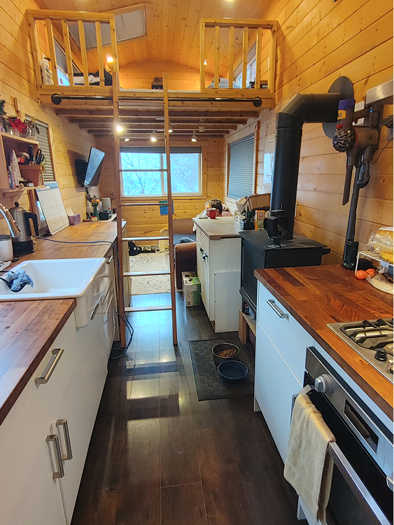 The interior of a tiny home with a loft for sleeping and small galley kitchen.