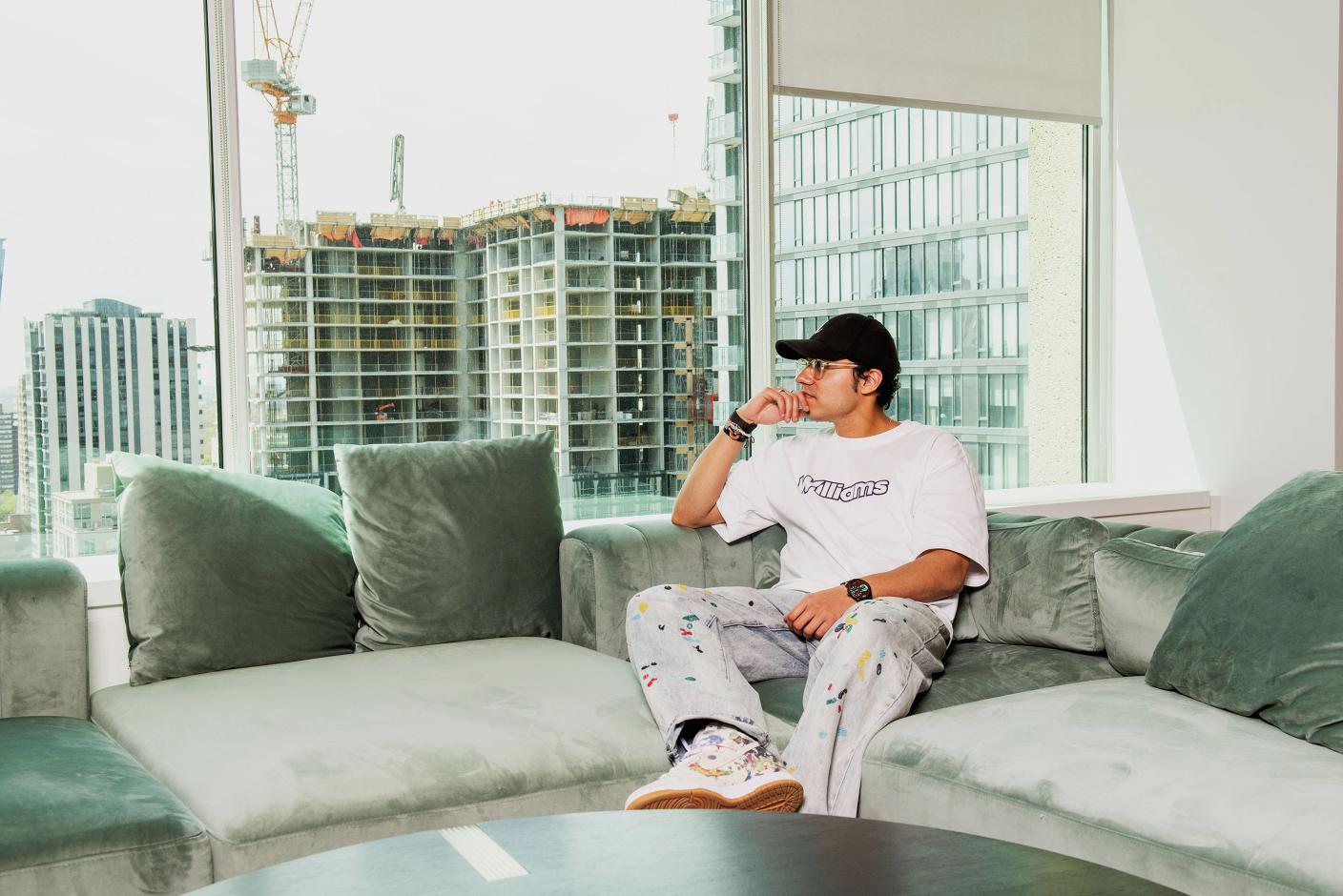 Swish Goswami sits on a couch looking out a window where under-construction building is visible