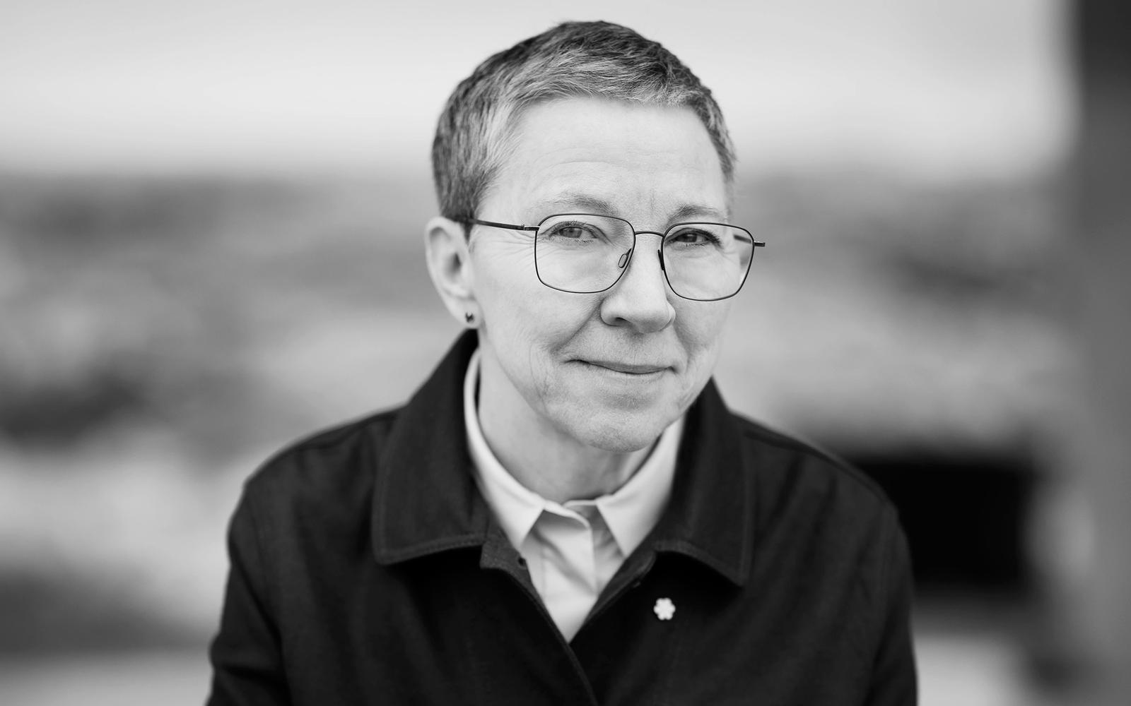 A portrait of Zita Cobb, depicted at the Fogo Island Inn on the staircase overlooking a set of benches and a set of antlers