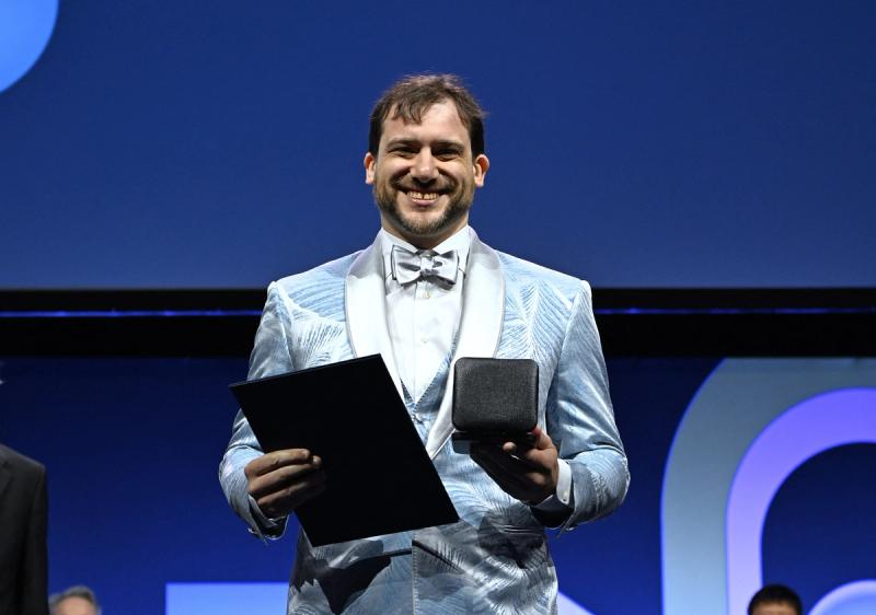 Jacob Tsimerman accepting the Fields Medal in a blue tuxedo.