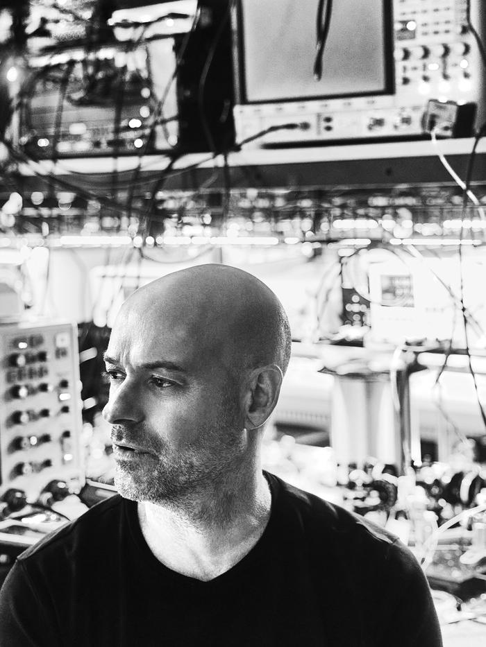 Side profile view of Christian Weedbrook, CEO of Xanadu, with a background of computer tech