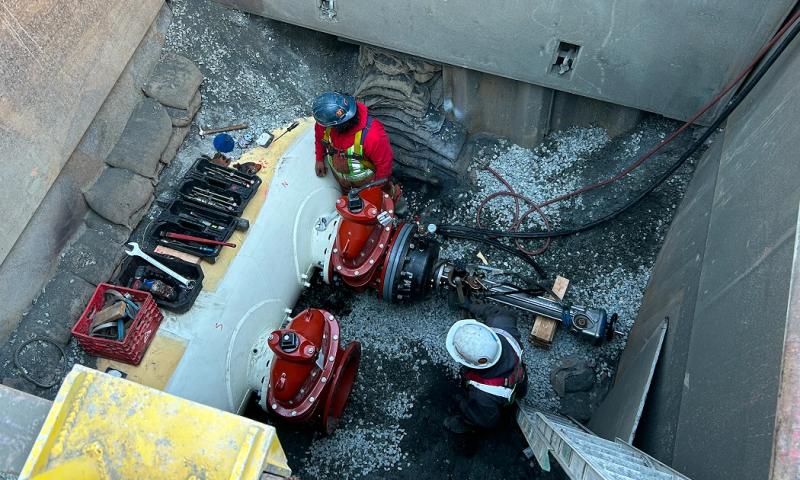A worker with the sewer tie-in at Sen̓áḵw.
