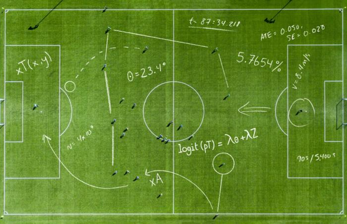 Aerial view of a soccer pitch overlaid with hand-drawn statistical equations, angles, and analytics notations