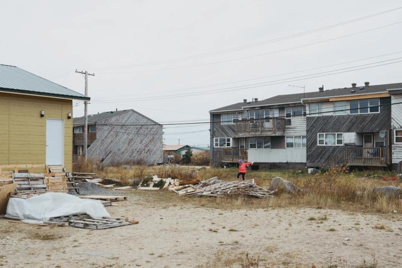 A girl walks over a pile of lumber in Churchill, Manitoba