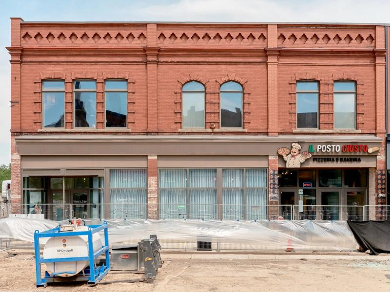 Storefronts on Grand River Street North in Paris, Ontario, including Il Posto Giusto and the adjacent storefronts near the site identified by local signage as the location of the first long-distance telephone call.