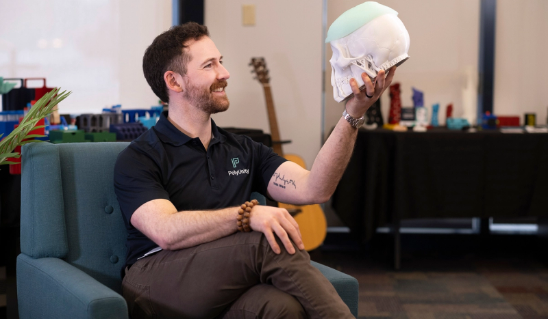 Man holds model skull in office