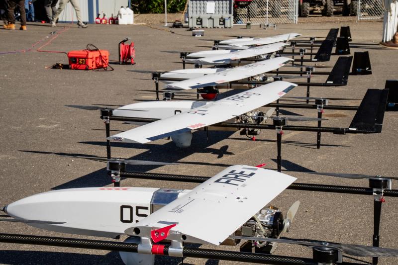 Anduril Industries SuperVolo aircraft, each with FIRE printed across a wing, line up during staging at Nenana Municipal Airport in Alaska on June 18, 2026. The fleet carried Trident Sensingâs red-domed sensors to scan for heat and Trillium cameras to zoom in and confirm a fire.