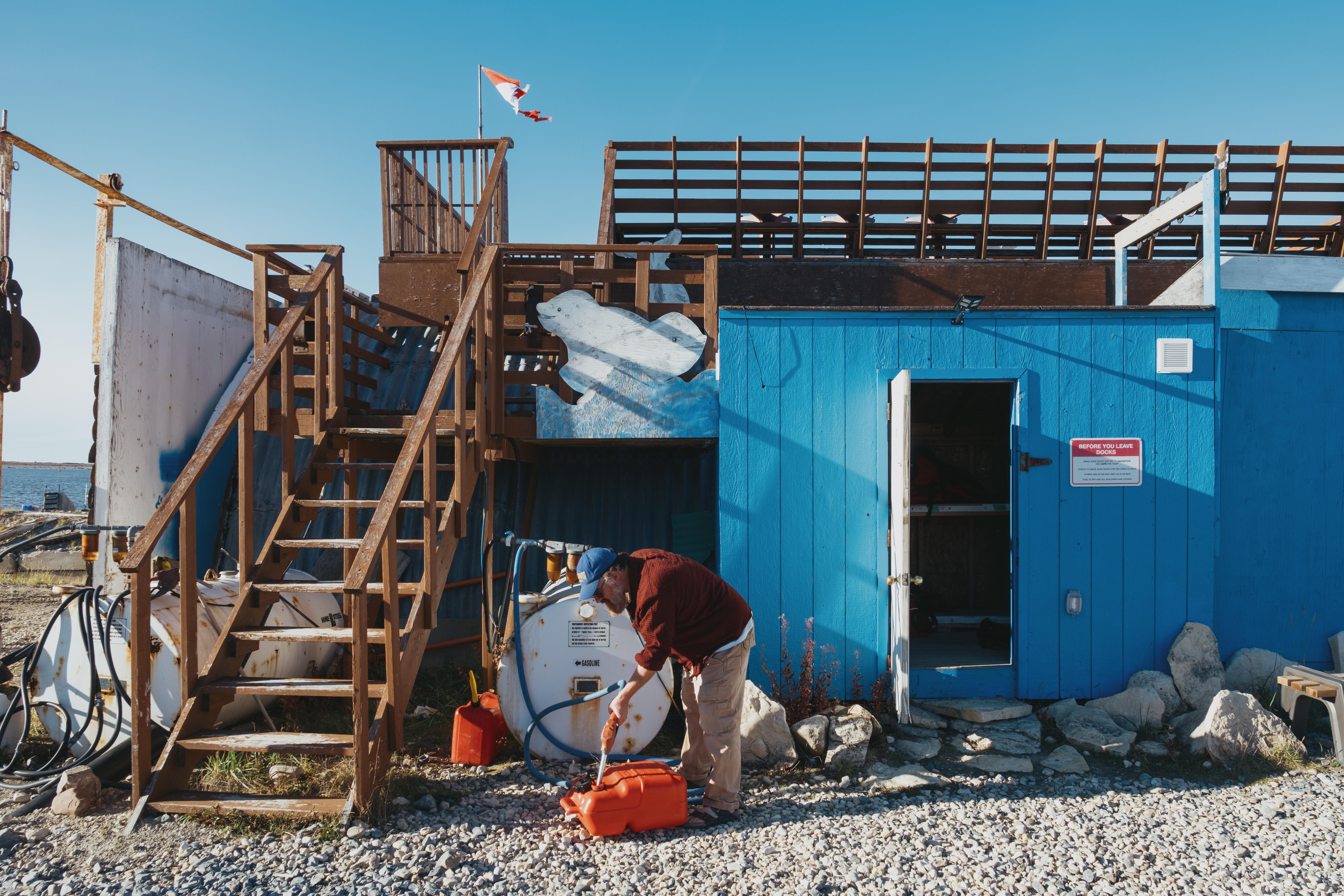 Man fills portable gasoline tank in Churchill, Man. outside home