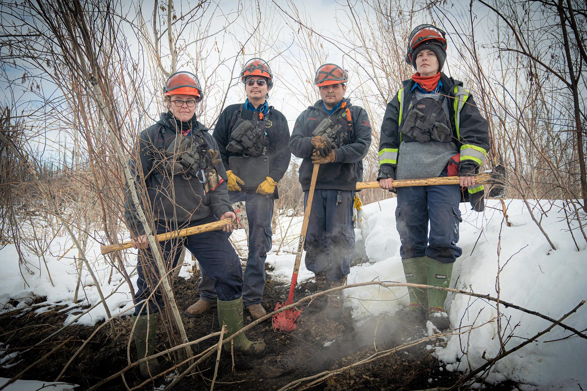 A group shot of the team hunting zombie fires in Canada, showing four people in wildfire fighting gear, From left to right: Sonja Leverkus, Ecosystem Scientist, Senior Fire Lead, Northern Fire WoRx (NFWRx);  Donovan Bertrand, Crew Leader NFWRx, member of Acho Dene Koe; David Wilmsmeier, Crew  Leader NFWRx, member of Prophet River First Nation; Alexis Jorgensen, Ecologist, NFWRx,  Fort Nelson, B.C.