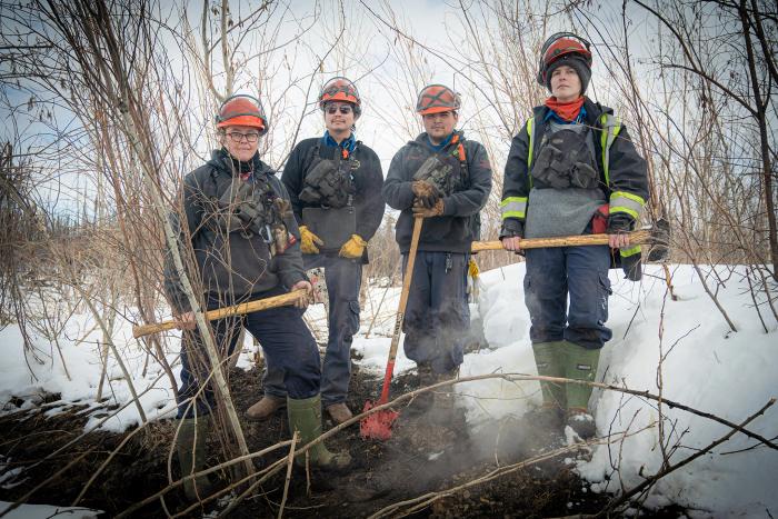 A group shot of the team hunting zombie fires in Canada, showing four people in wildfire fighting gear, From left to right: Sonja Leverkus, Ecosystem Scientist, Senior Fire Lead, Northern Fire WoRx (NFWRx);  Donovan Bertrand, Crew Leader NFWRx, member of Acho Dene Koe; David Wilmsmeier, Crew  Leader NFWRx, member of Prophet River First Nation; Alexis Jorgensen, Ecologist, NFWRx,  Fort Nelson, B.C.