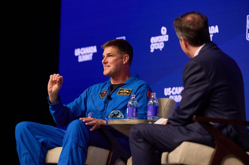 Canadian astronaut Jeremy Hansen in his blue jumpsuit speaking on stage at the US-Canada Summit in Toronto