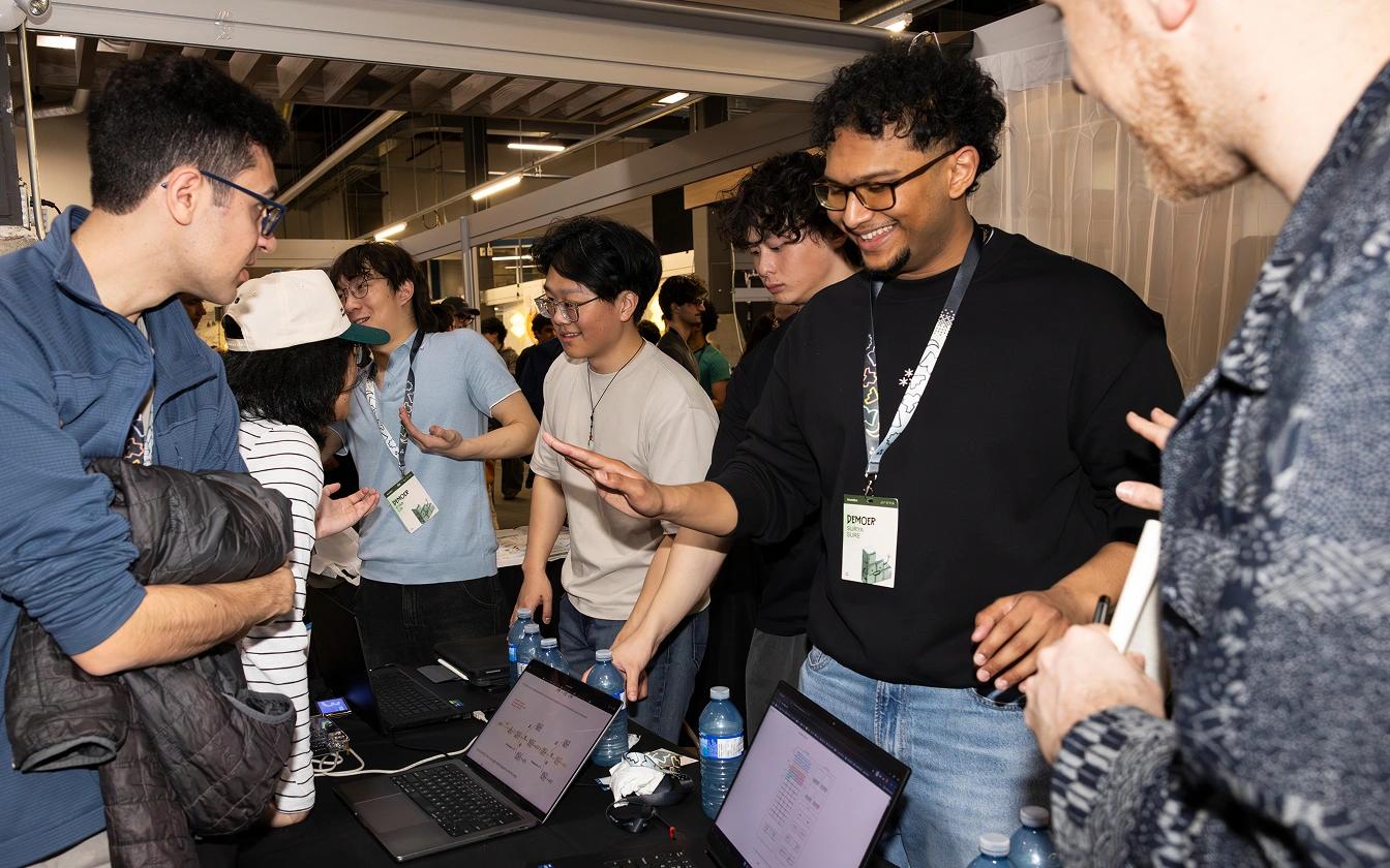 Students wearing badges on lanyards – TinyTPU's Evan Lin, Kenny Guo, Xander Chin and Surya Sure – demonstrating their innovations on laptops and smiling at the 2026 Socratica Symposium, a weekend-long University of Waterloo event in Kitchener, Ont.