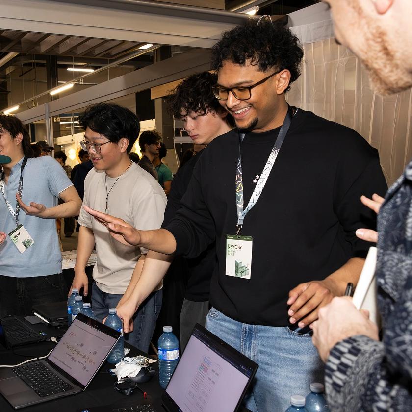 Students wearing badges on lanyards – TinyTPU's Evan Lin, Kenny Guo, Xander Chin and Surya Sure – demonstrating their innovations on laptops and smiling at the 2026 Socratica Symposium, a weekend-long University of Waterloo event in Kitchener, Ont.