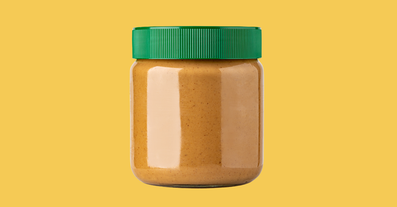 Peanut butter jar with green lid on a yellow background