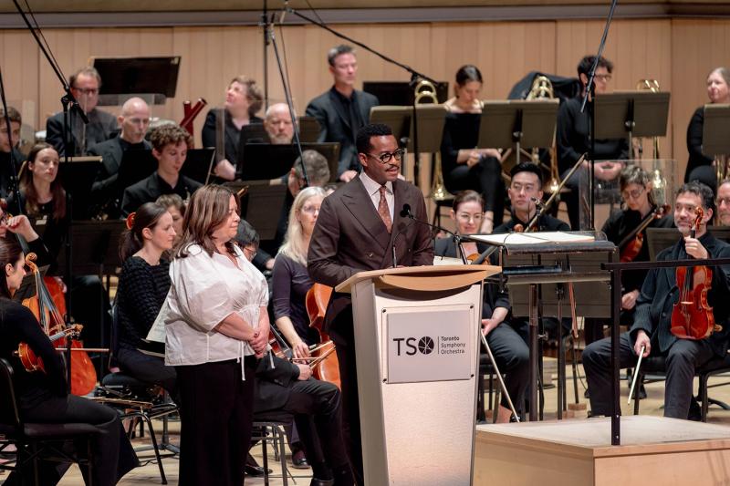 TSO CEO on stage with Williams on stage with Lori Spadorcia, senior vice president, public affairs, partnerships and chief strategy officer at CAMH with the orchestra in the background on April 30, 2026 at the world premiere of the Art of Healing's Still Here