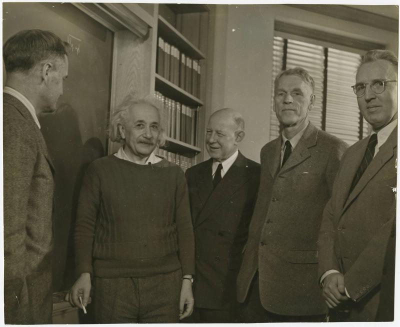 Albert Einstein, a founding faculty member of the Institute for Advanced Study, in an office on its campus with other faculty members. From left to right: James Alexander, Einstein, Frank Aydelotte (the facility's director), Oswald Veblen and Marston Morse.