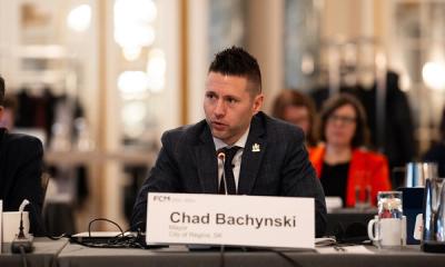 Regina Mayor Chad Bachynsky seated at a forum, speaking into a microphone.