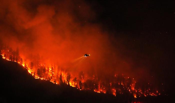 A helicopter prepares to drop water on the Quilpituk Creek wildfire on the west side of Okanagan Lake near Fintry, B.C., August 3, 2026.
