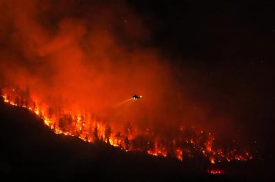 A helicopter prepares to drop water on the Quilpituk Creek wildfire on the west side of Okanagan Lake near Fintry, B.C., August 3, 2026.