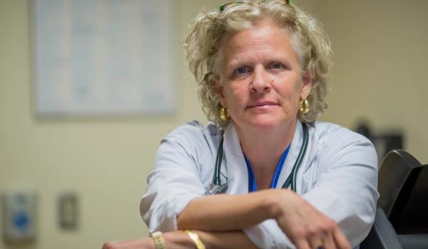 A portrait of cardiologist Dr. Heather Ross, shown from the chest up wearing a stethoscope and looking at the camera with her arms crossed