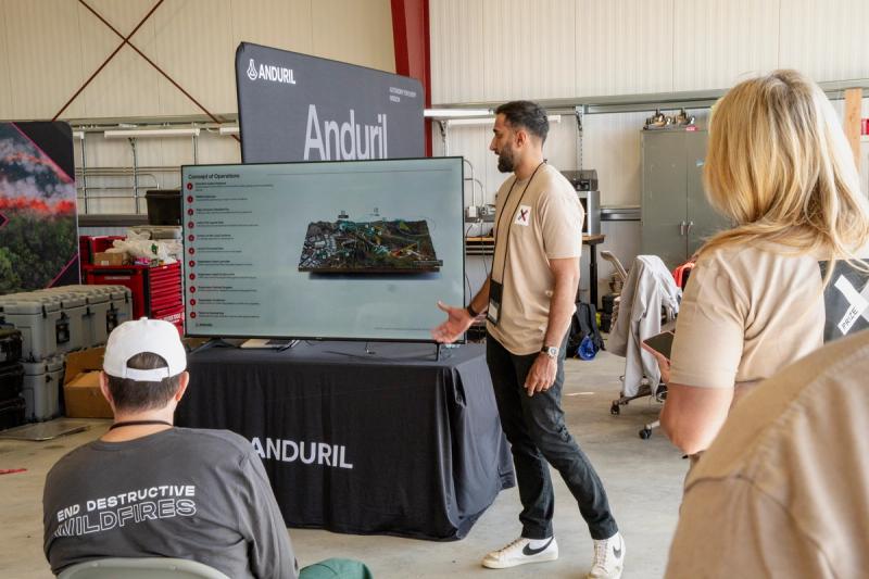 An XPRIZE staff member leads a briefing in Anduril Industriesâ hangar at Nenana Municipal Airport in Alaska on the morning of the companyâs trial, June 19, 2026.