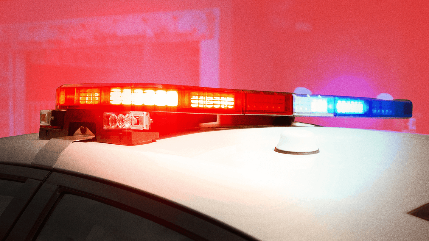 A photo illustration of a flashing police vehicle siren, shown in closeup on top of a white vehicle, against a reddish illustration background, for a piece on AI use for 911 calls in Canada