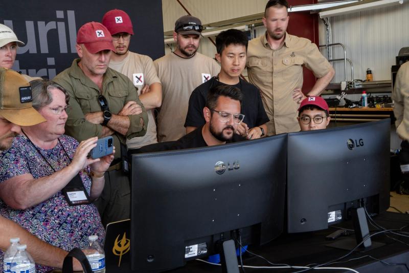 XPRIZE officials and Anduril Industries engineers crowd the monitors late on June 19, 2026, in Nenana, Alaska. Shortly after 6:20 p.m., a Trident sensor aboard one of Andurilâs SuperVolo aircraft registered the dayâs first real fire, which a Trillium camera confirmedâbut an unrelated aircraft landing on the road kept Andurilâs suppression drone grounded.