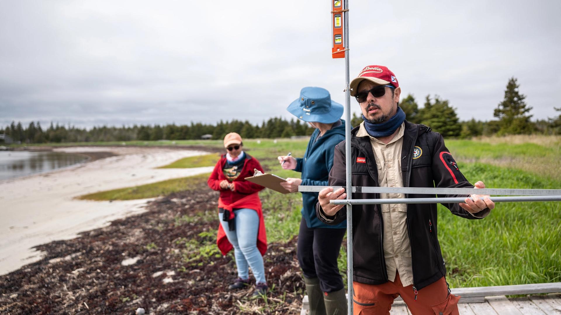 Coastal geographer Camilo Botero measures erosion levels with a device made from four dollar-store curtain rods in Black Duck Cove Provincial Park in Little Dover, N.S., on June 14, 2026.