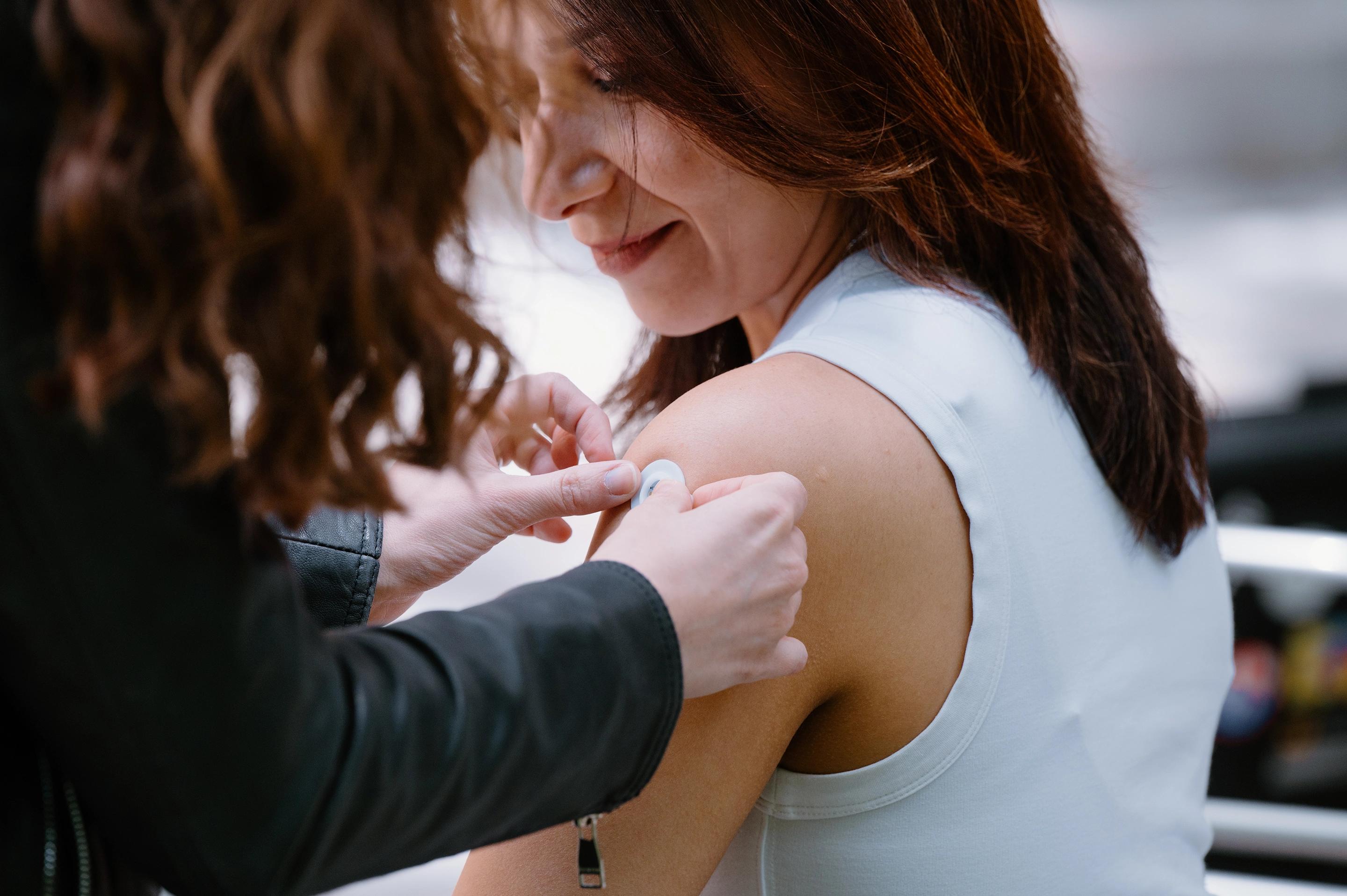 A portrait of Mahla Poudineh wearing gloves and holding tweezers that hold her co-creation, the the Wearable Aptalyzer, a painless wearable device that can track molecules in the body in real time