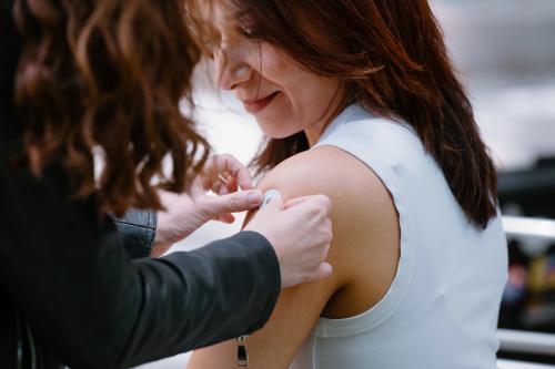 A portrait of Mahla Poudineh wearing gloves and holding tweezers that hold her co-creation, the the Wearable Aptalyzer, a painless wearable device that can track molecules in the body in real time