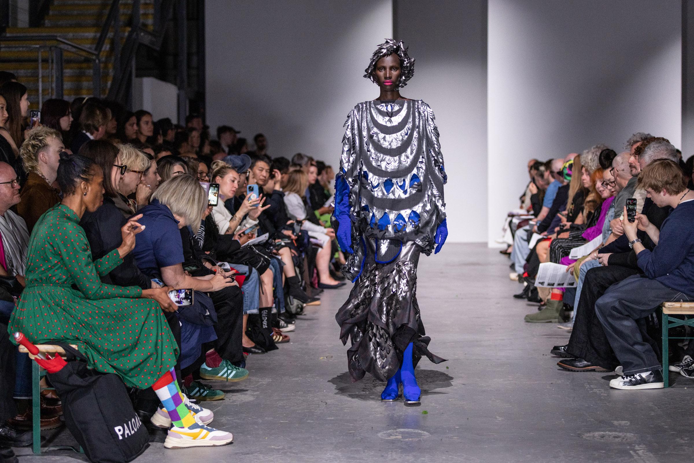 Model in a silver and blue dress walking down the catwalk at the Westminster Fashion Students' catwalk show.