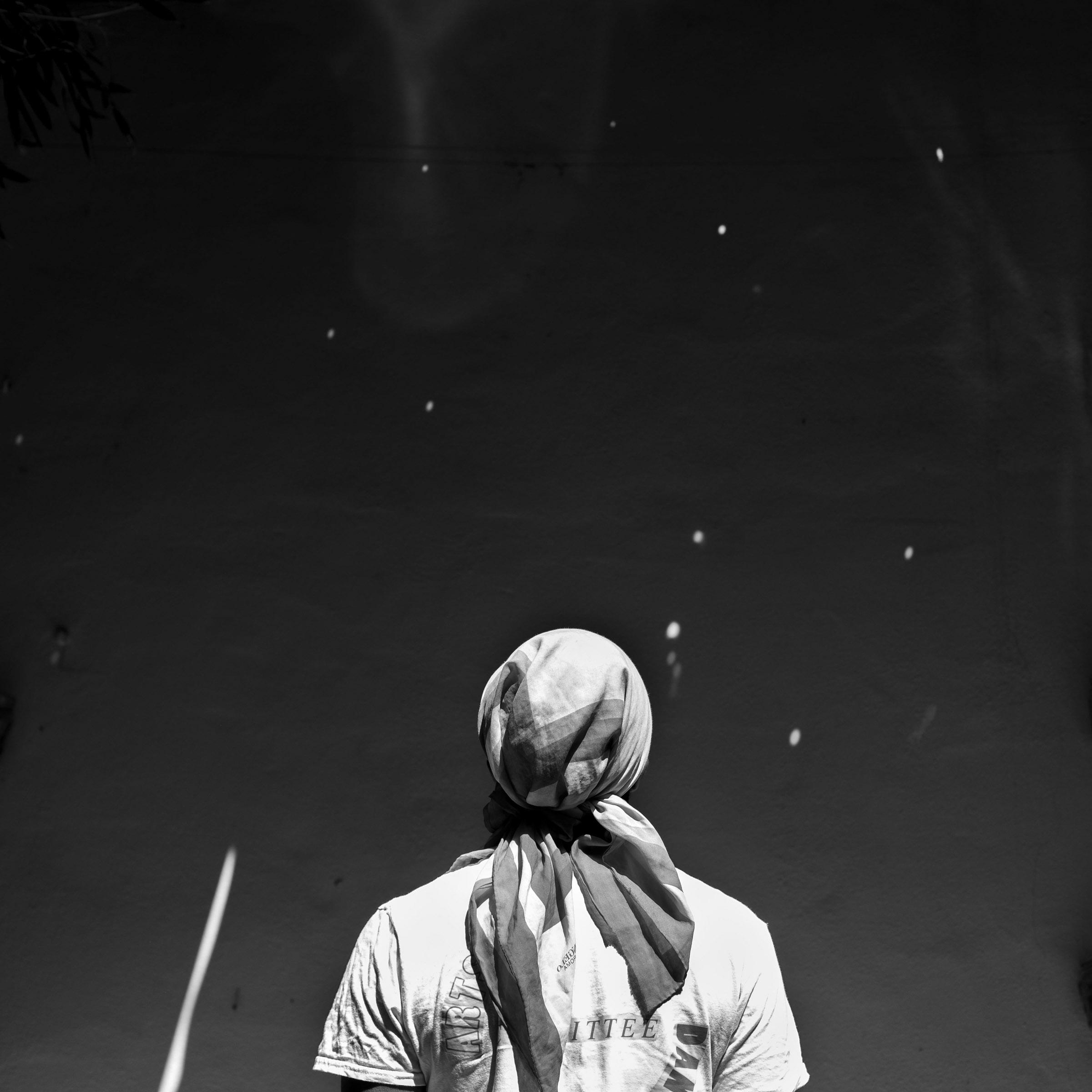 Black and white photograph of a man looking up at the stars in the nighttime sky. A photograph by Gian Luca Urdiroz.